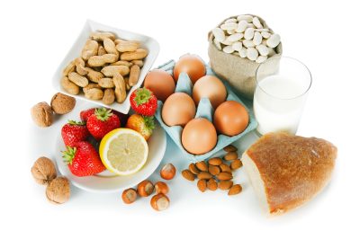 Allergy food concept - bread, milk, fruits, nuts, eggs and beans on white background